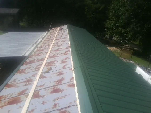 Old rusted panels beside newly installed green metal roofing — Wind Damage Roof Repair by Roofing Brothers in Algonac
