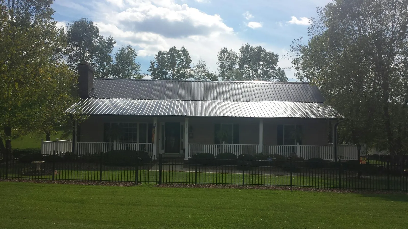 Gray metal roof on a brick ranch with a full width front porch — Gutter Guard Installation work by our crew in Algonac