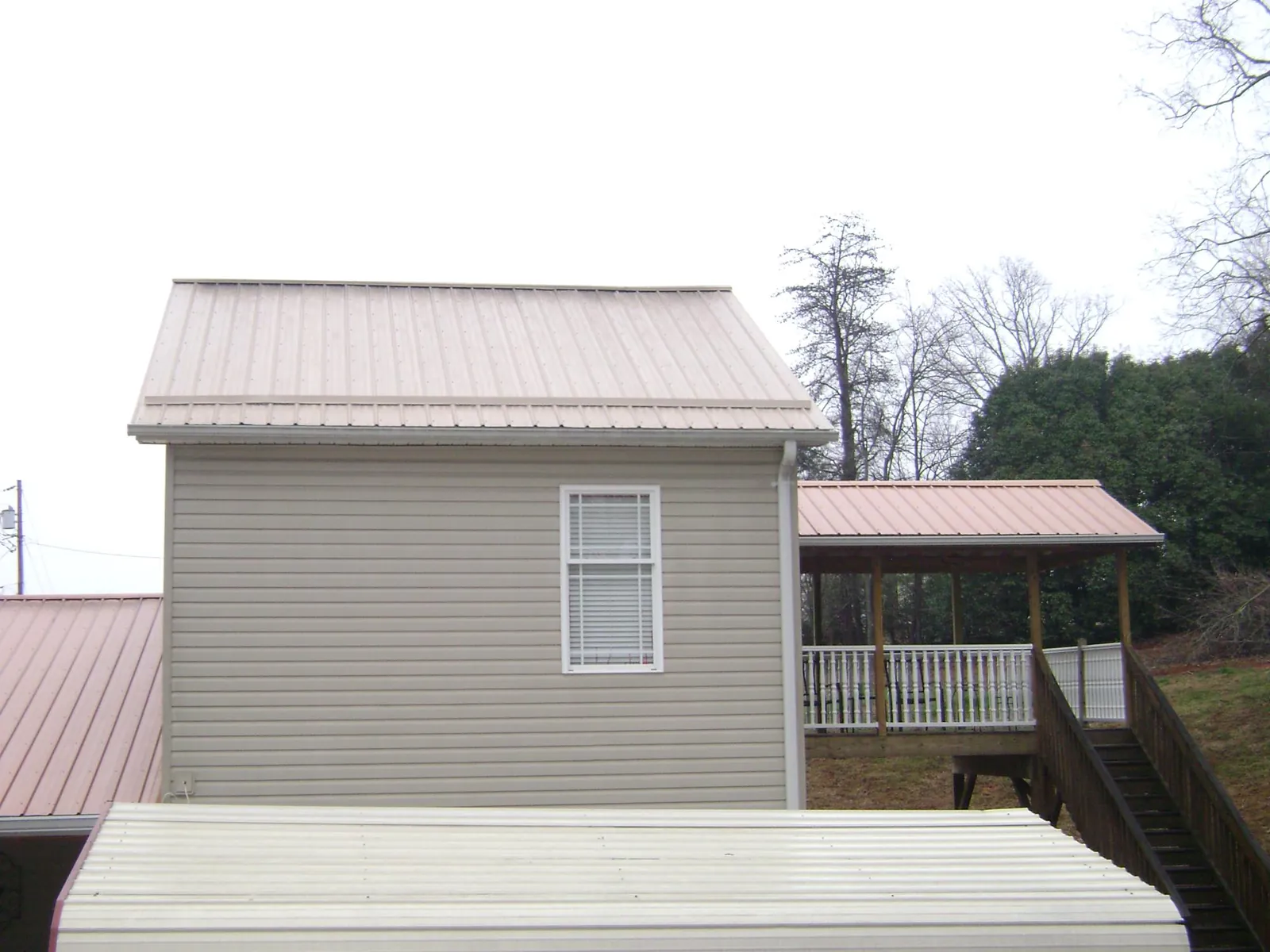 Tan metal roofs on a two story addition and attached porch, from a Roof Replacement job in Algonac