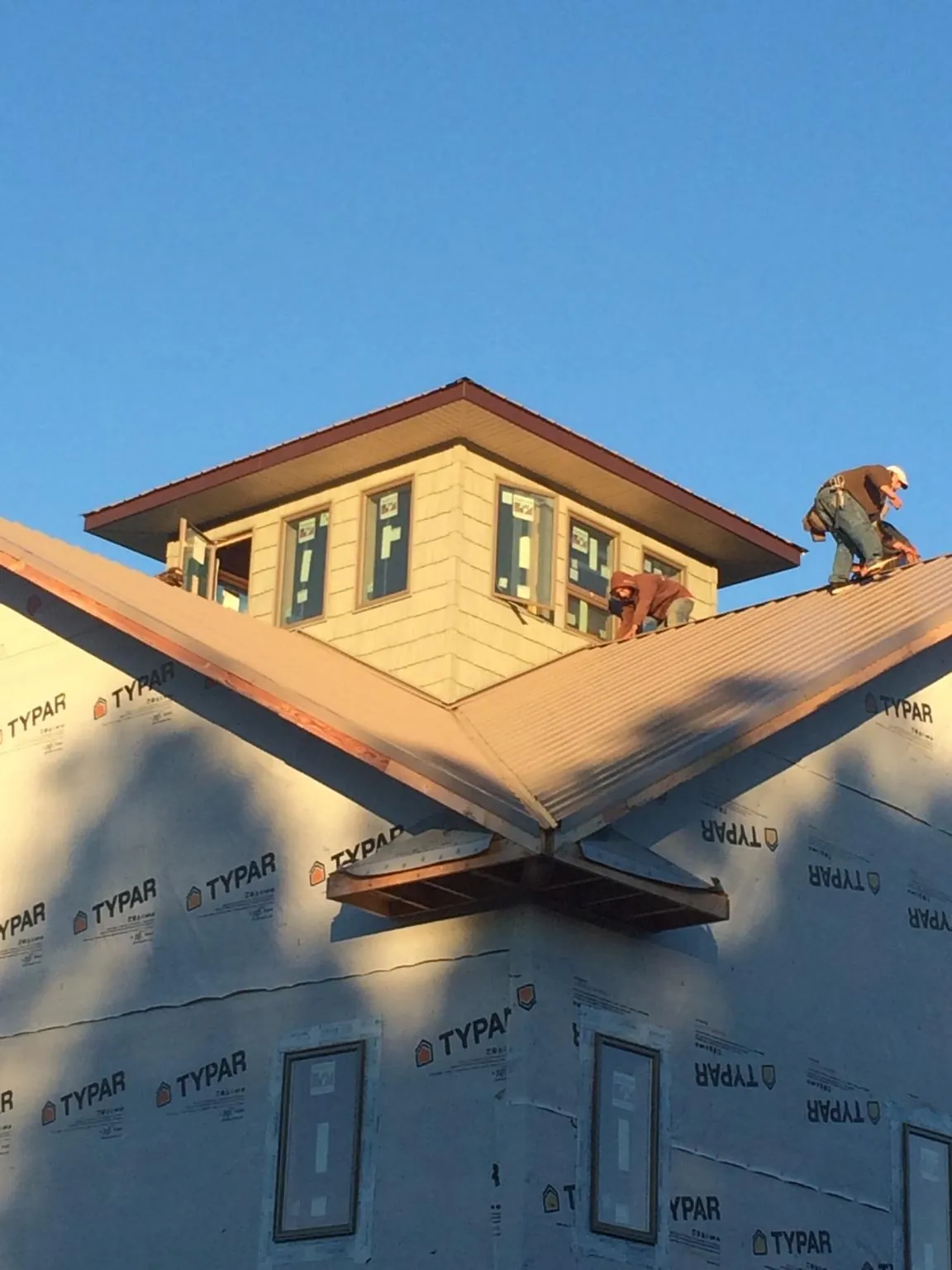 Roofers working around a rooftop cupola on a new metal roof at sunset — Roof Waterproofing in Algonac by Roofing Brothers